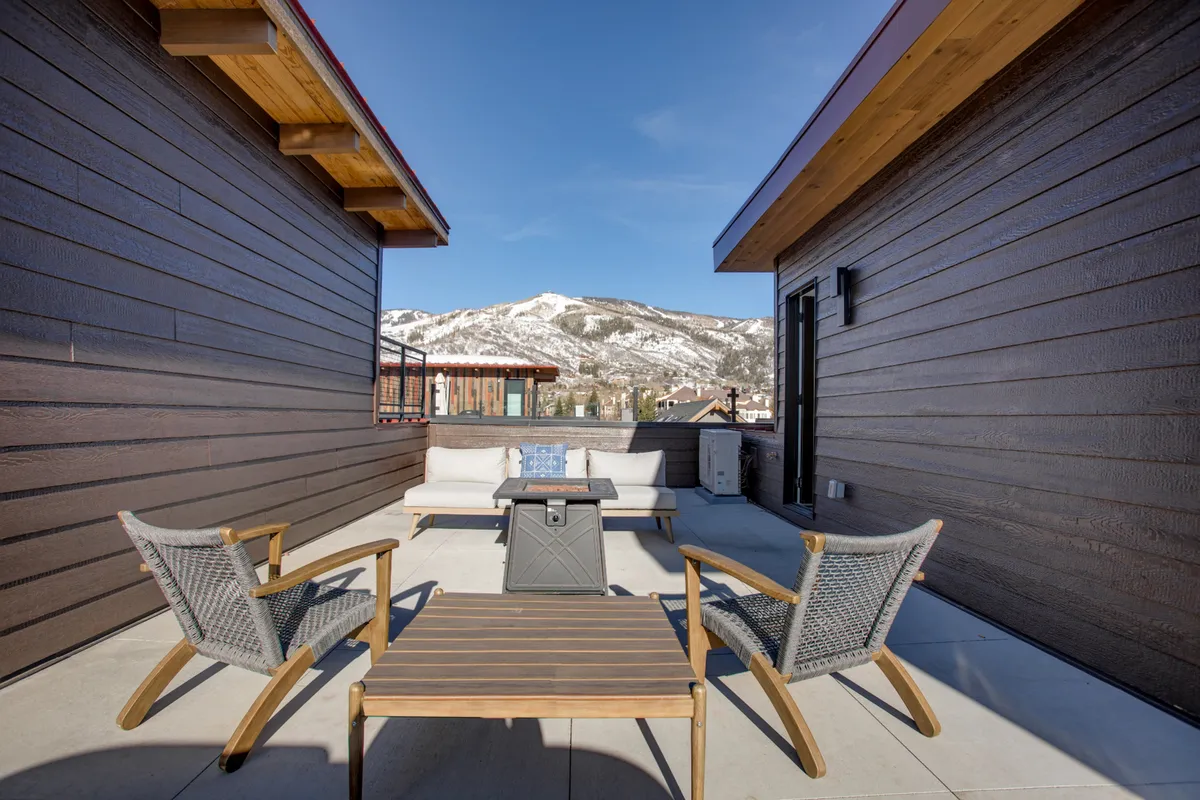 An outdoor seating area with comfortable furniture and a coffee table, set against a breathtaking mountain backdrop. The space invites groups to relax, socialize, and enjoy the scenic surroundings, day or night.