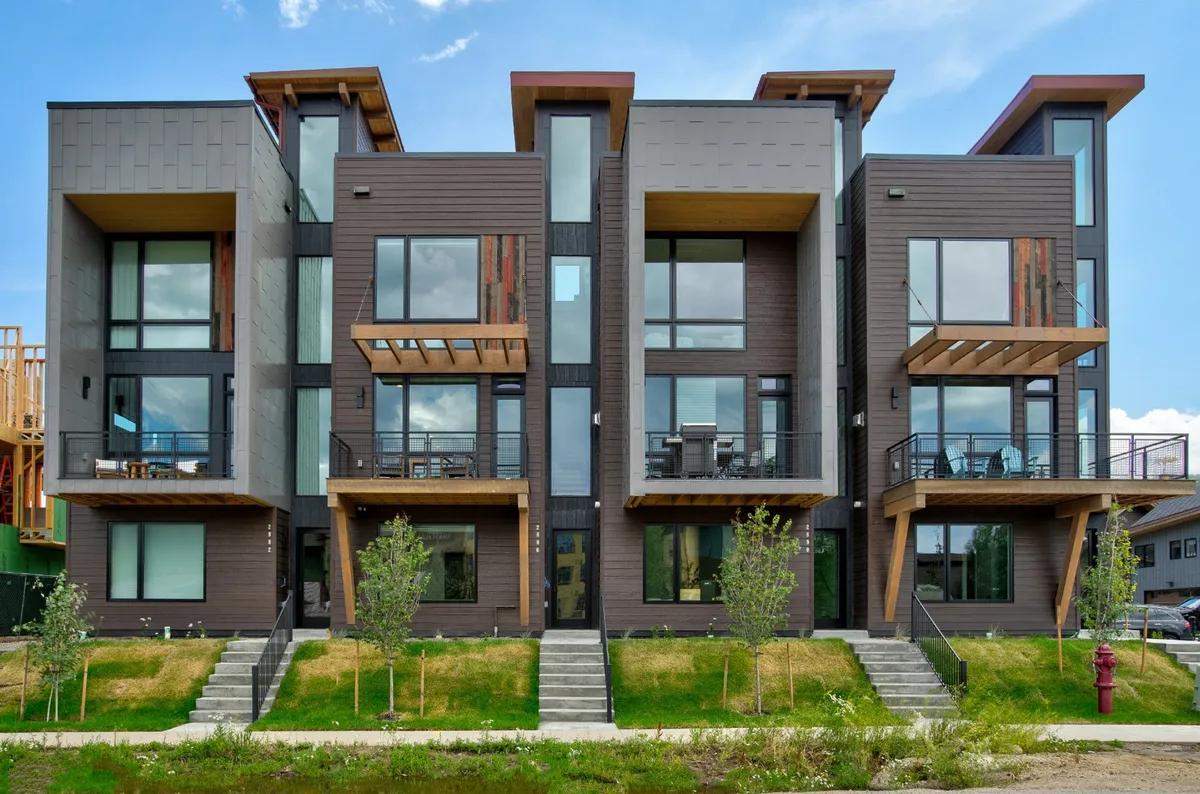 An exterior shot showcasing the property’s modern architecture, large windows, and multiple balconies, surrounded by attractive landscaping. The lively scene hints at social gatherings and seamless access to community amenities.
