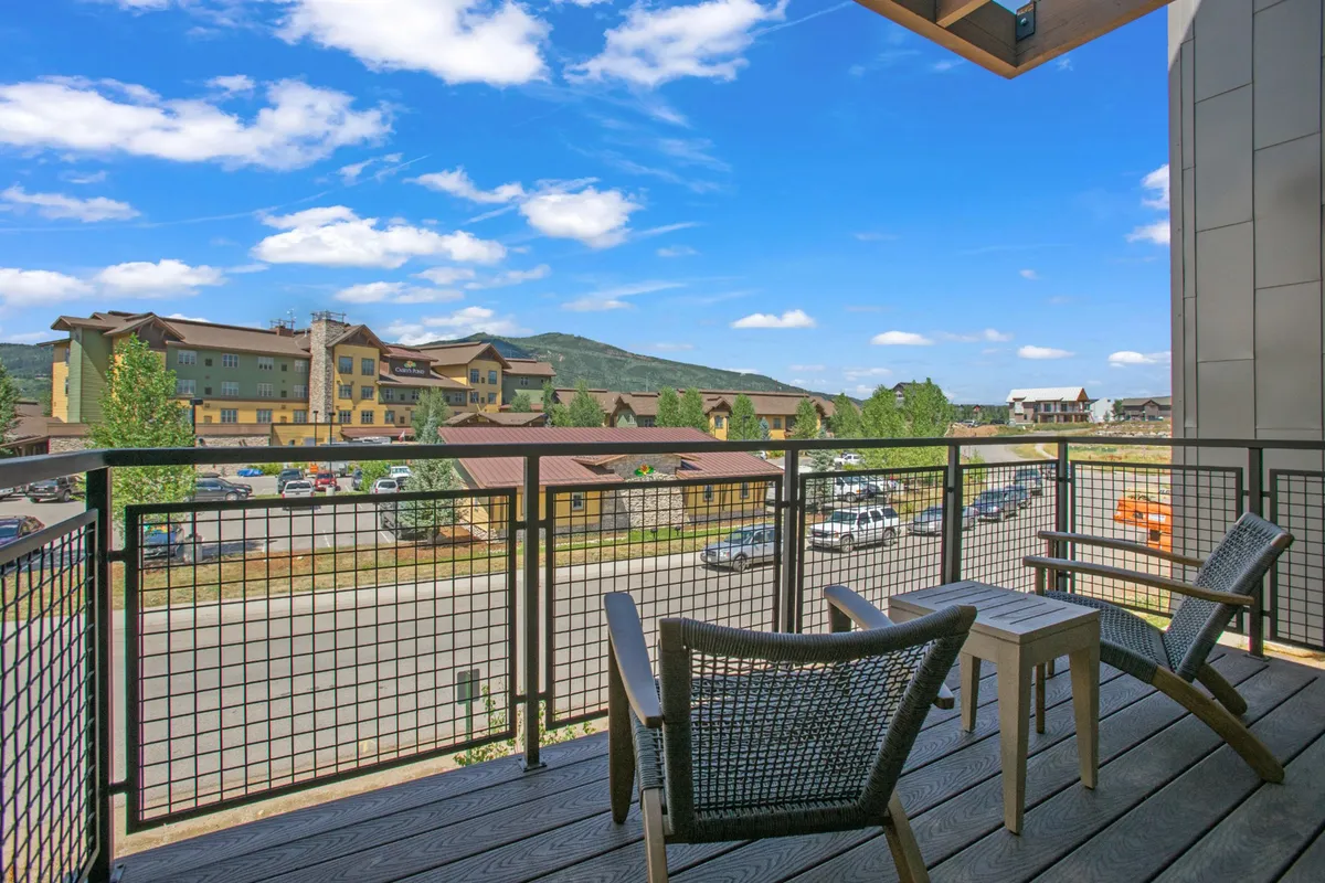 An outdoor balcony seating area overlooks stunning mountain views, offering a tranquil space for relaxation or social gatherings. The setting is ideal for enjoying fresh air, morning coffee, or an afternoon barbecue with the gas grill.